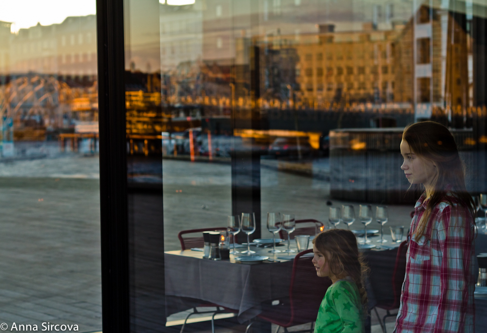 kids look out at the sunset from the Copenhagen Royal Theater restaurant with the cityscape reflecting in the big glass of the restaurant